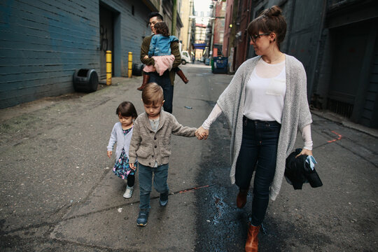 Family of five walking together in city alley way