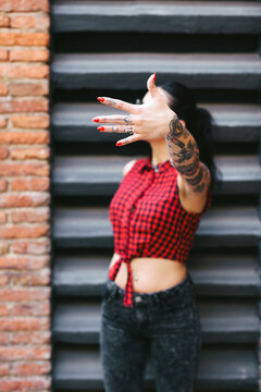 Young alternative woman covering her face with a hand.