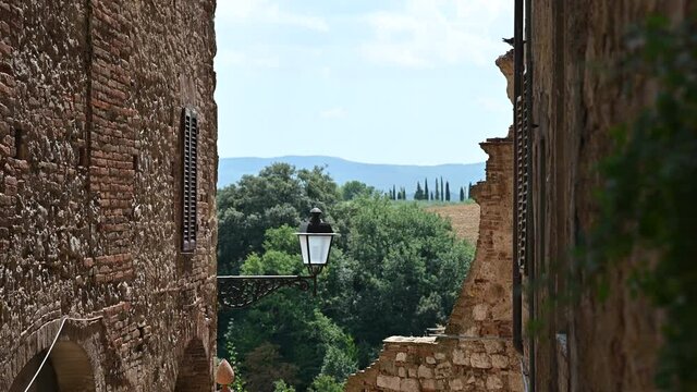 Colle di Val d'Elsa, Tuscany, Italy. August 2020. Tilt footage on a street in the historic center: beyond the walls enchanting views full of charm, in the countryside you can recognize the cypresses.