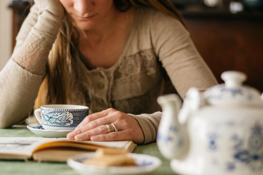 Woman reading a book and dinking tea