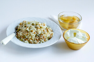 Traditional Turkish rice pilaf with peas and noodles on white with yogurt and compote