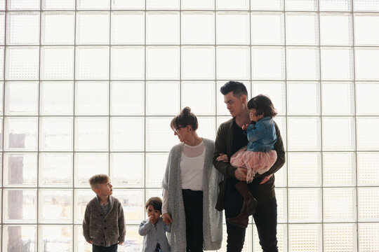 Family of five talking together in front of window grid