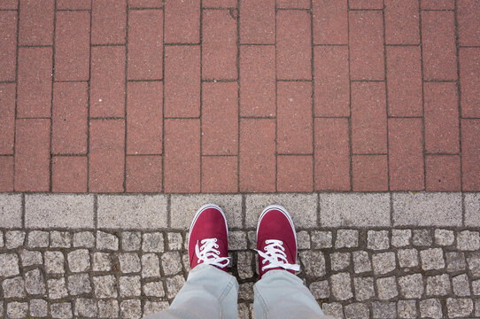 Red sneakers on street, red stones, footsie, personal perspective