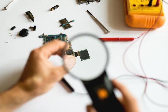 Man using magnifying glass on cellphone chip