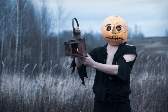 Lost in the woods a guy in a pumpkin with a lantern with a candle wanders in search of a means of getting rid of the autumn depression