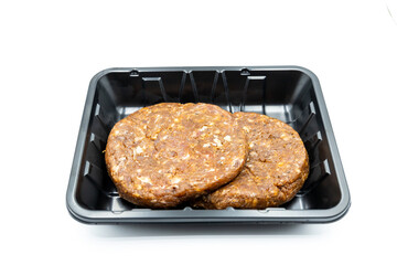 Raw burger meat in a black plastic package isolated on white background, top view.