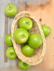 green apples in basket on wooden table