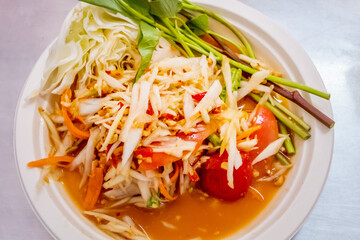 Green papaya salad in white paper plate. Spicy thai food.