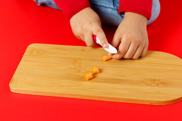 Little child hands cutting baby carrots on table