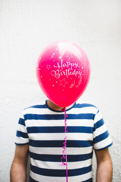 Man is hiding behind a ""happy birthday"" balloon