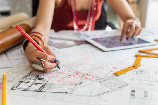 Close-up of hands of female architects working on blueprint