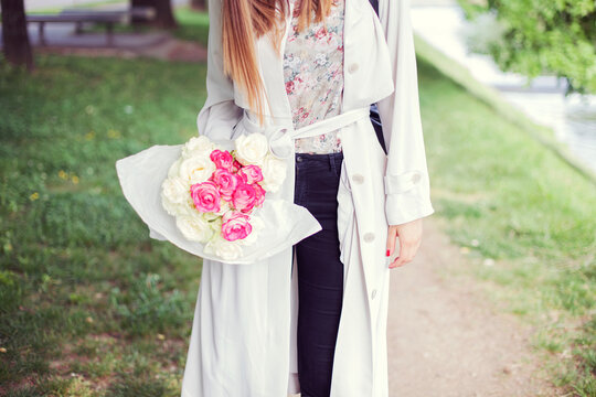 Young woman walking in the park with a bouquet of roses