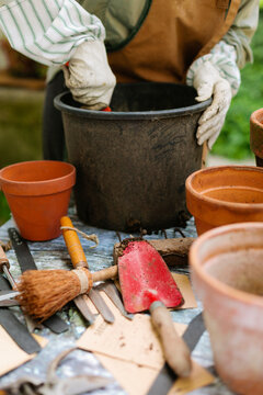 Detail of gardener digging with show inside big pot on gardening table