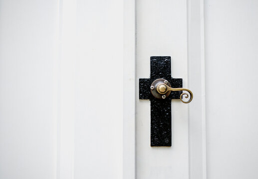 Decorative doorknob of a church is in the shape of a cross