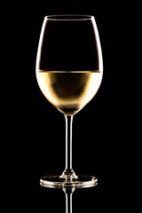 White wine chardonnay glass with moody dramatic back lighting isolated on black background