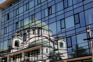 Obraz na płótnie Canvas Reflection of the Temple of St. Sava in the Serbian capital of Belgrade in the windows of the building