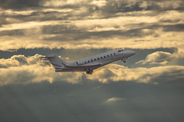 White small private turbofan-powered twin-engine business jet airplane flying in air after takeoff...