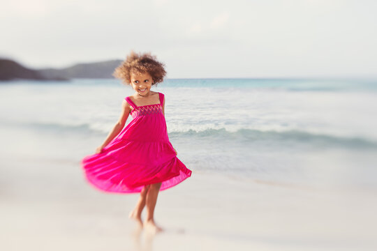 Young girl in pink playing on the beach