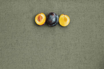 Whole plum and sliced plum on a table cloth; Fresh plums prepared to eat