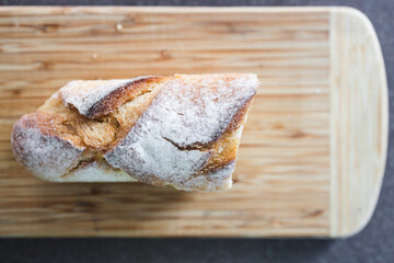 simple food ingredients, piece of baguette bread on cutting board with knife slicing it