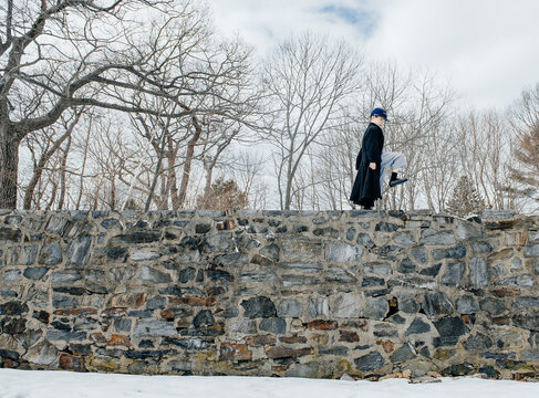 Boy pretending to be a Union soldier marches on a tall stone wall