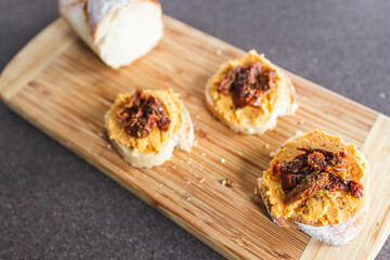 plant-based food, vegan snack with paprika hummus on sliced baguette bread topped with sundried tomatoes