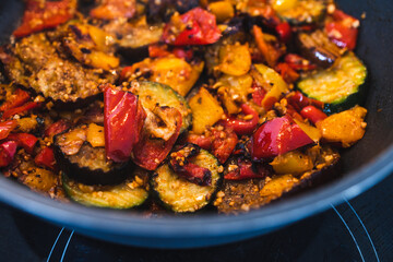 plant-based food, vegan eggplant zucchini and red pepper mix getting sauteed on a pan with mixed spices and fresh tomatoes
