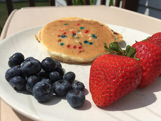 Patriotic Pancakes with Red, White and Blue Sprinkles and a Side of Strawberries and Blueberries on a White Plate for Labor Day, Memorial Day, or 4th of July / Independence Day