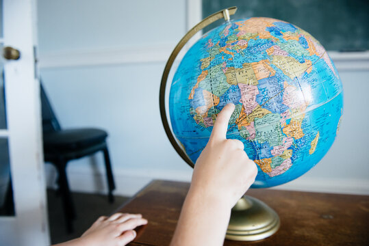 Hands of a child point to Africa on a classroom globe