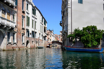 canal in Venice with residential buildings off to the side and a gondola in the foreground awaiting a ride