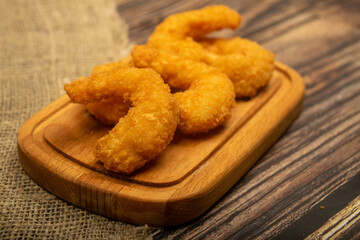 Atlantic prawns fried in batter on a wooden serving Board. Close up.