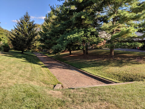 Empty Water Drainage Easement with Ditch and Green Grass on All Sides and Trees in the Distance