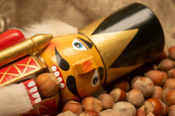 Nutcracker wooden figure of a soldier for cracking nuts on the background of scattered nuts. Traditional symbol of Christmas and New Year. Close up.