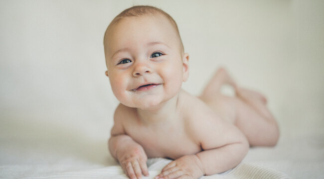 Cute, happy baby boy on tummy - solid background