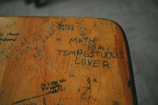 graffiti scratched into school desk top