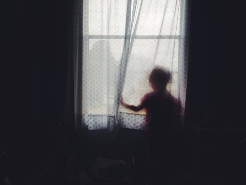 silhoutte of child behind sheer curtain