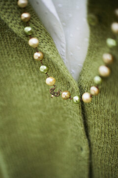 Extreme close up of ancient green and white pearls necklace on woolen cardigan