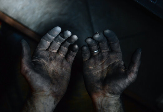 Man's hands covered in black soot