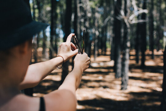 Girl in the forest playing with a little homemade slingshot