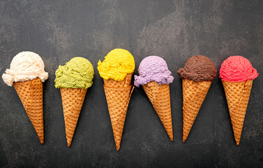 Various of ice cream flavor in cones blueberry ,green tea ,pistachio ,almond ,orange and cherry setup on dark stone background . Summer and Sweet menu concept.