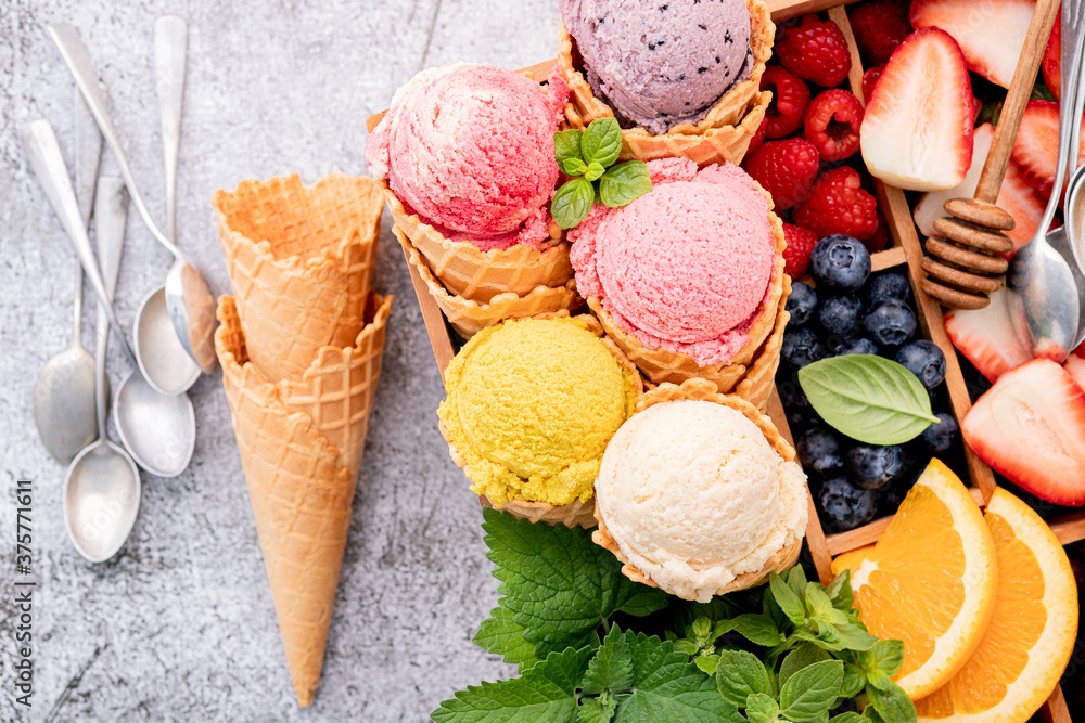 Poster various of ice cream flavor in cones with berries in wooden box setup on concrete background . summe