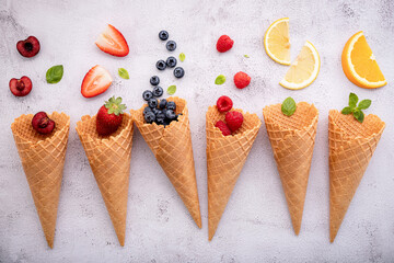 Various of fruits  in cones blueberry ,strawberry ,raspberries and strawberry setup on white stone background . Summer and Sweet menu concept.