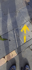 Shadow of a pilgrim and his boots next to a yellow arrow