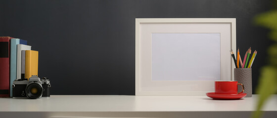 Worktable with mock up frame, camera, books, stationery and copy space