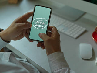 Male office worker texting on mock up smartphone at worktable