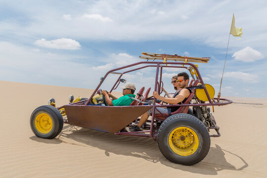 Dune buggy with passengers speeding across open ground