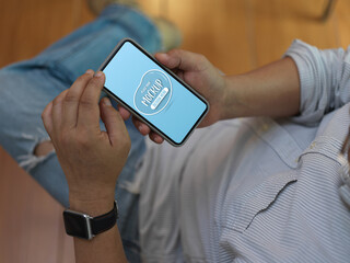 Male worker using mock up smartphone while relaxed sitting on office chair