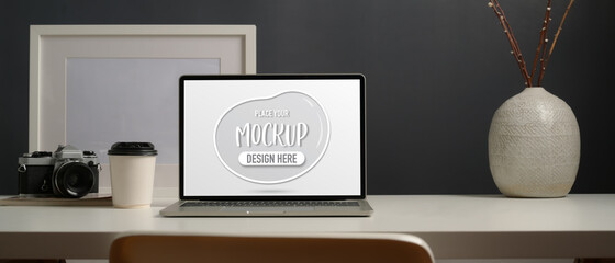 Worktable with mock up laptop, camera, frame, decorations and copy space in modern home office