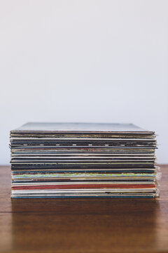 A stack of vinyl records on a wooden table