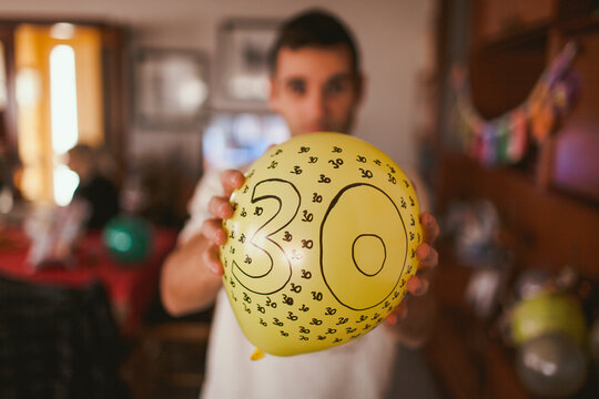 Man holding balloon with number 30